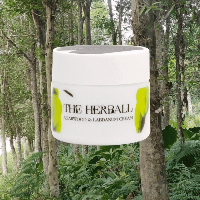 A white jar of agarwood and labdanum cream with trees in the background