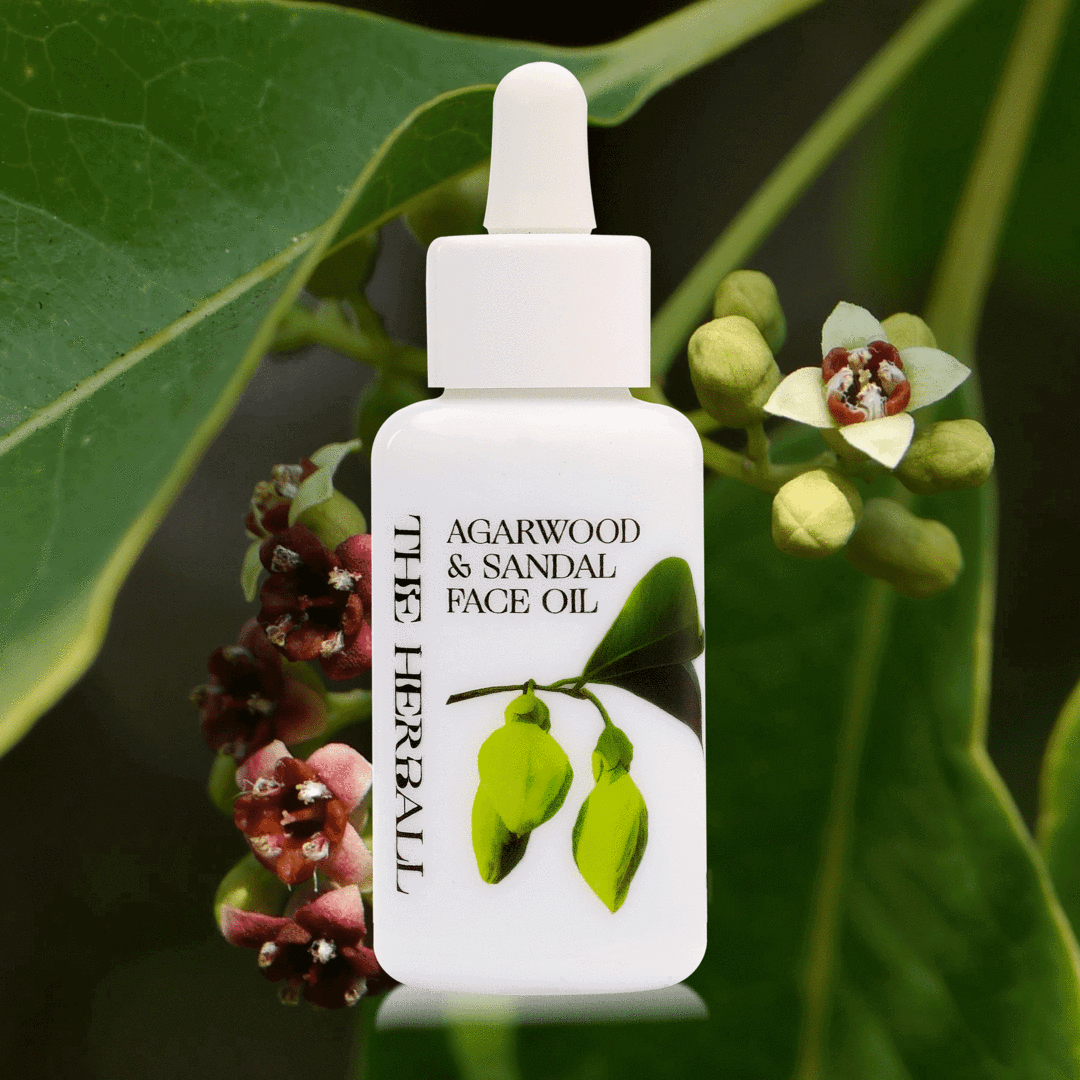 A white bottle of face oil with green leaves and sandalwood flower in the background.