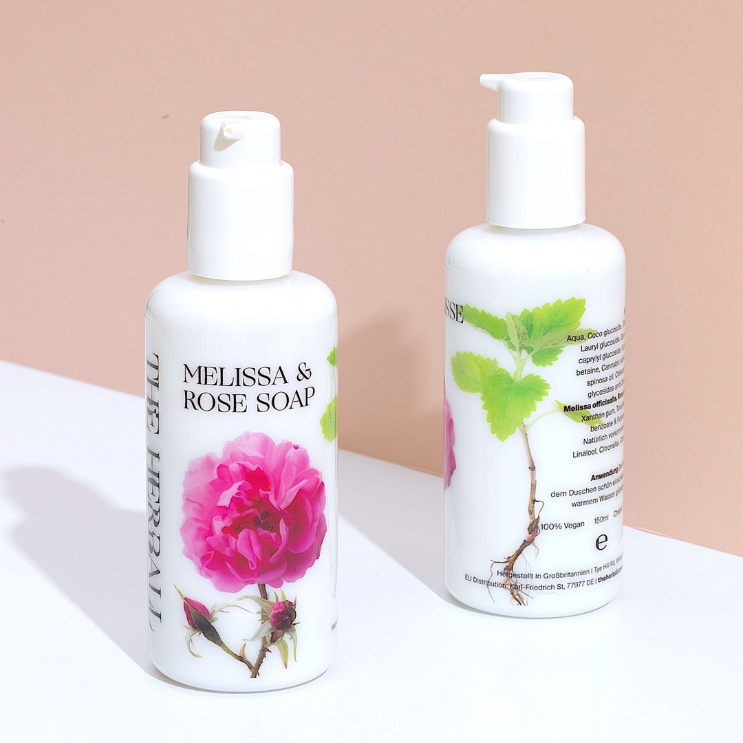 A white bottle with pump showing on the label melissa & rose soa, rosa damascena flower and The Herball logo.
