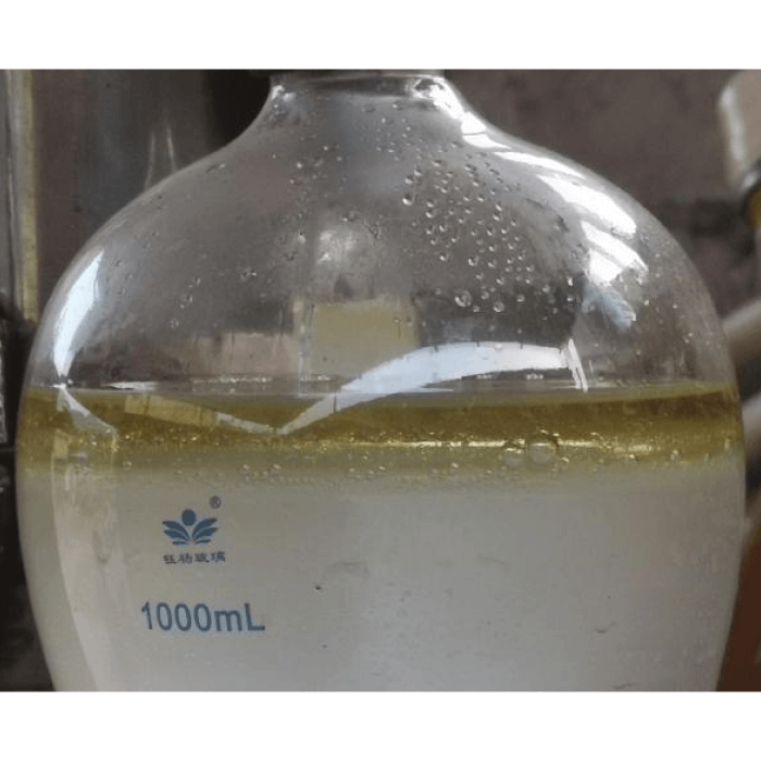 A transparent test tube of 1000ml containing a white liquid with a brown layer on the surface.